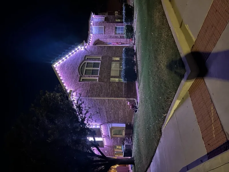 Permanent holiday lighting in pink on a brick corner-lot home in DFW