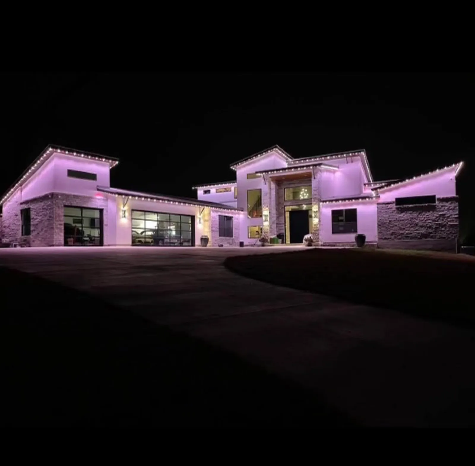 Permanent outdoor lighting in warm white on a modern stone home in DFW