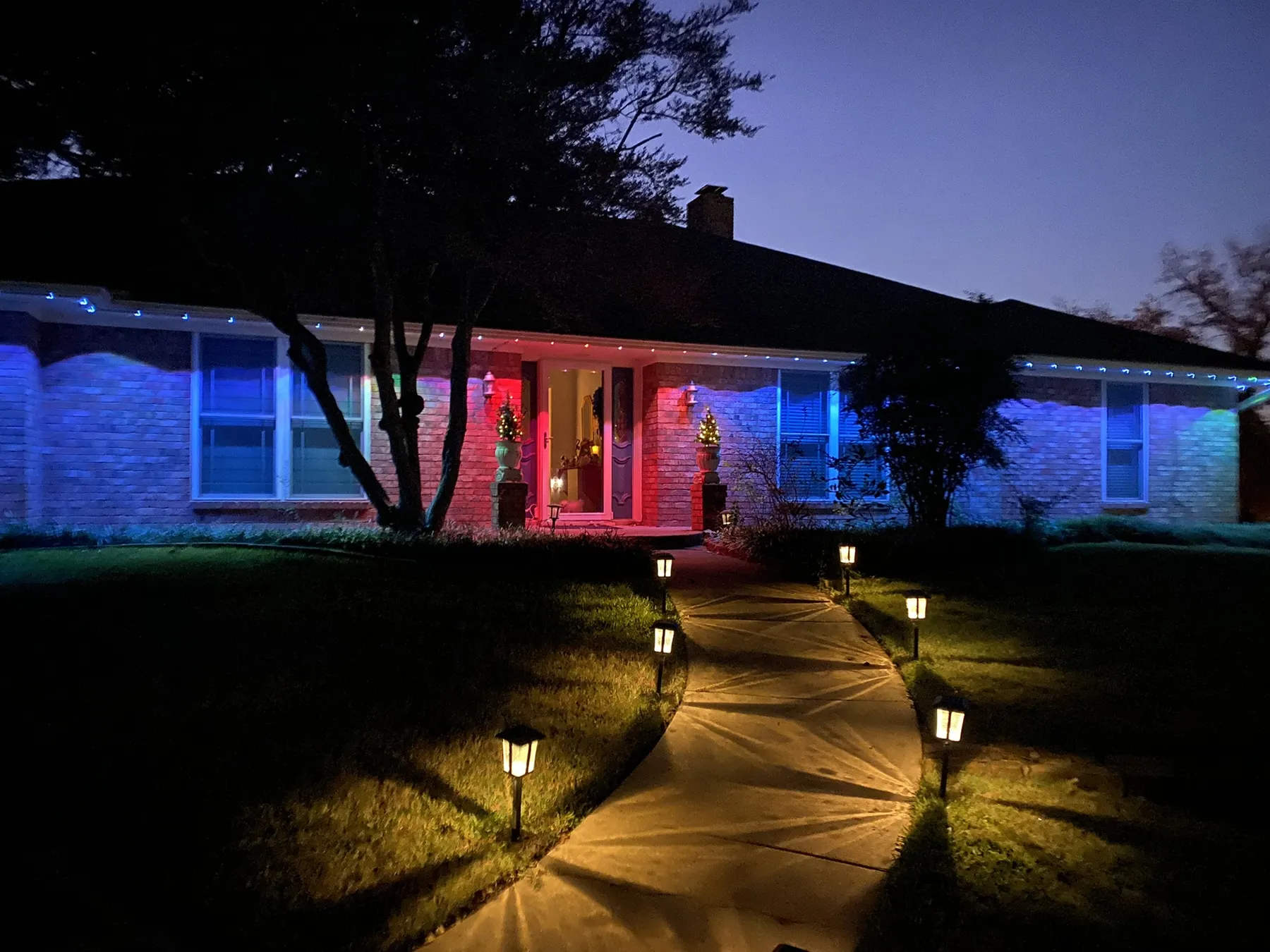 Permanent eave lighting in blue and red on a single-story brick home in DFW at dusk
