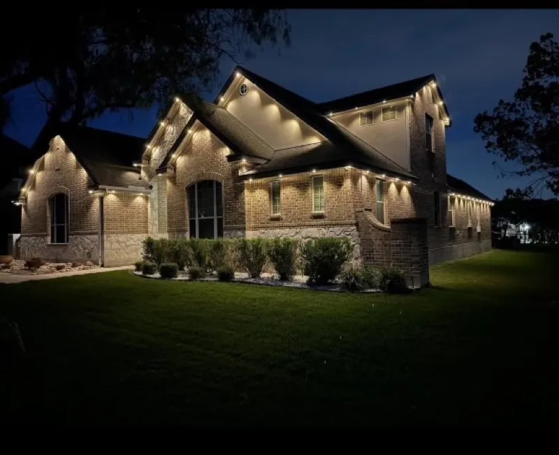 Permanent outdoor lighting in warm white on a stone and brick home in DFW