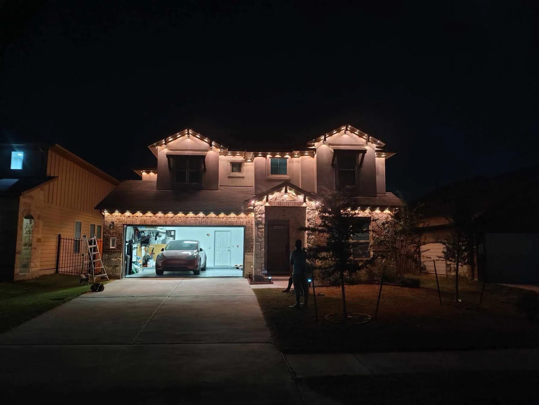 Warm white accent lighting on a two-story stucco and stone home in DFW at night