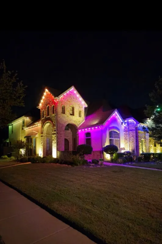 Permanent Christmas lights in magenta and purple on a two-story brick home in DFW