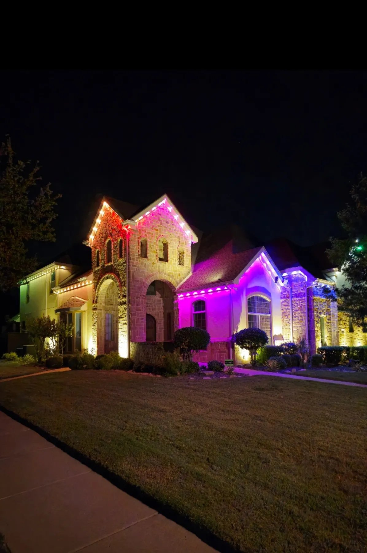Permanent Christmas lights in magenta on a two-story brick home in DFW